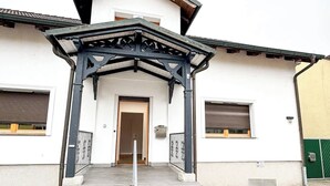Ein Gebäude mit weißer Fassade, einer Holztür und einem schwarzen Metallvorsprung.