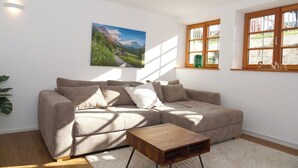 Una sala de estar con un sofá seccional color beige, una mesa de centro de madera y un cuadro grande de paisaje en la pared.