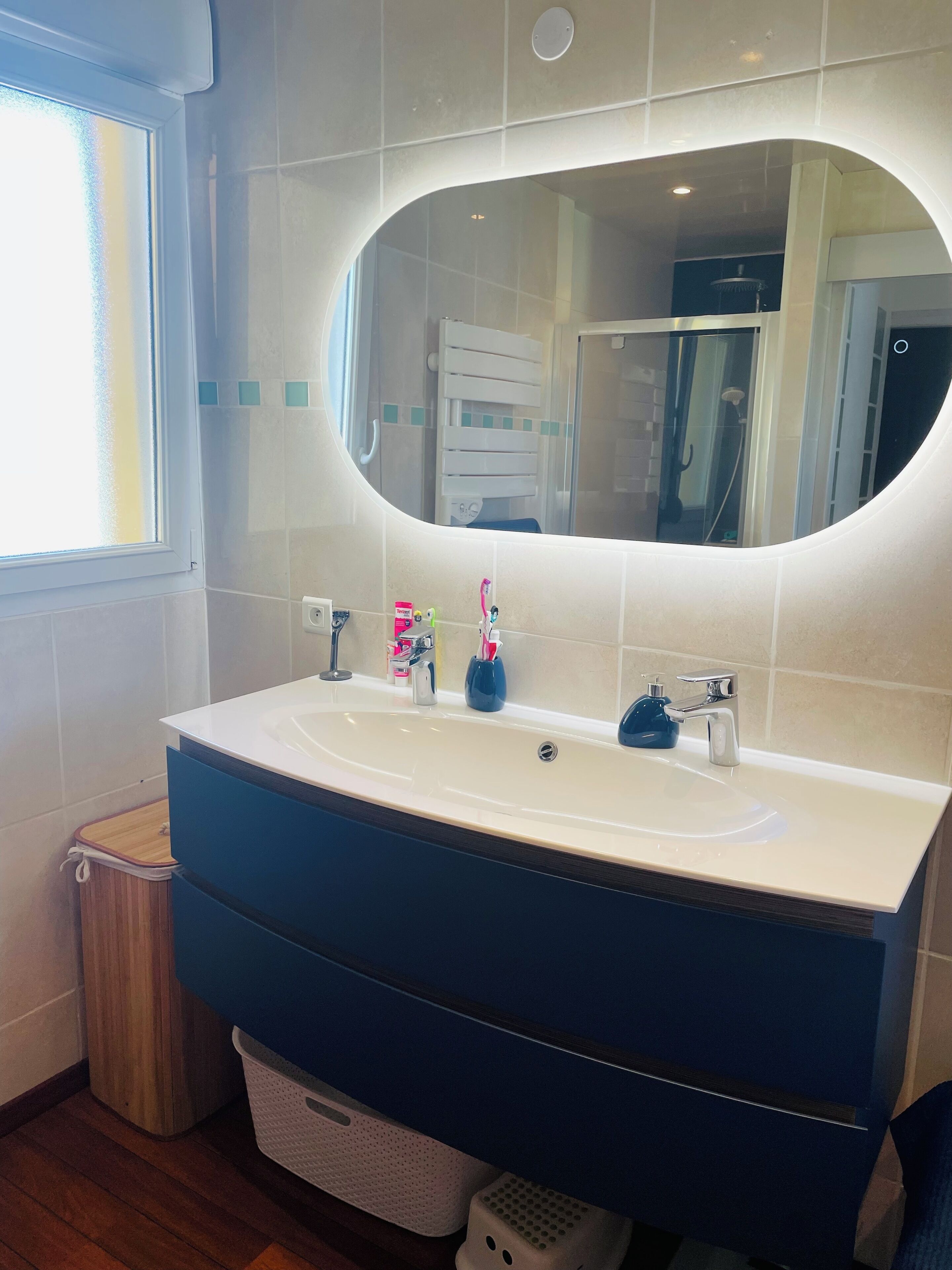 Een badkamer met een wit wastafel, een blauwe kast en een grote spiegel.