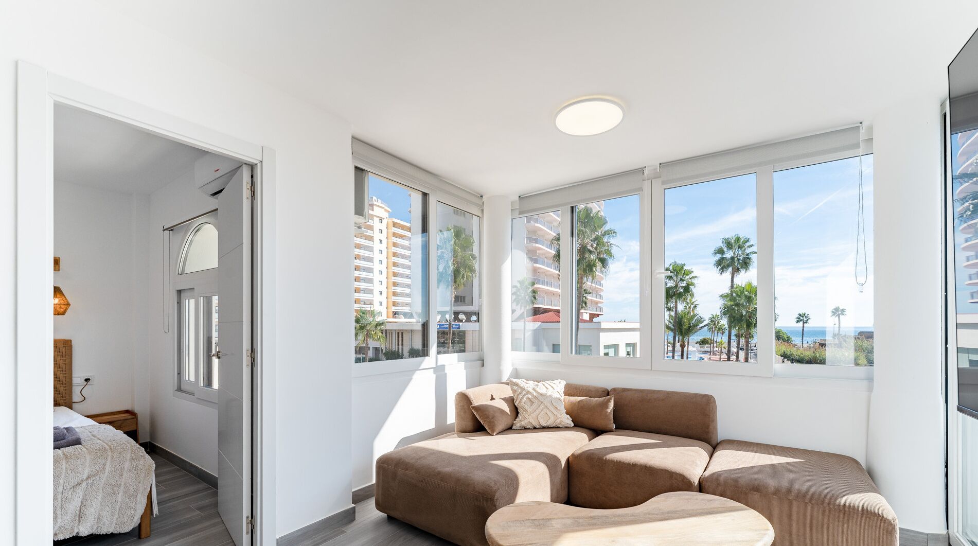 A modern bedroom with a large window, a sofa, and a bed.
