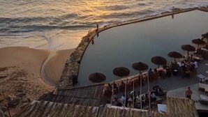 Ein Strandresort mit Pool, Sonnenschirmen und Blick auf den Sonnenuntergang.