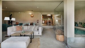 Ein modernes Wohnzimmer mit Sofa, Couchtisch und einem Essbereich im Hintergrund.