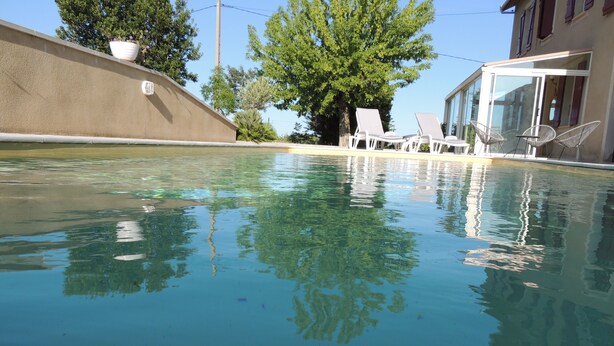 Ein klares Schwimmbecken mit Spiegelungen von Bäumen und einem Gebäude.