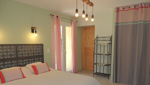 Ein Schlafzimmer mit einem Bett, einem Nachttisch, einer Wandleuchte und einer Tür zu einem anderen Raum.