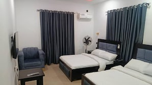 Quarto de hotel com duas camas, um sofá, uma TV, um ventilador e um ar condicionado.