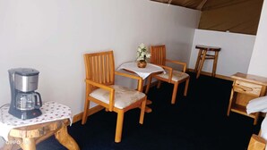 Ett litet, ombonat rum med två trästolar, ett litet bord med en kaffebryggare och ett träbord som används som nattduksbord.