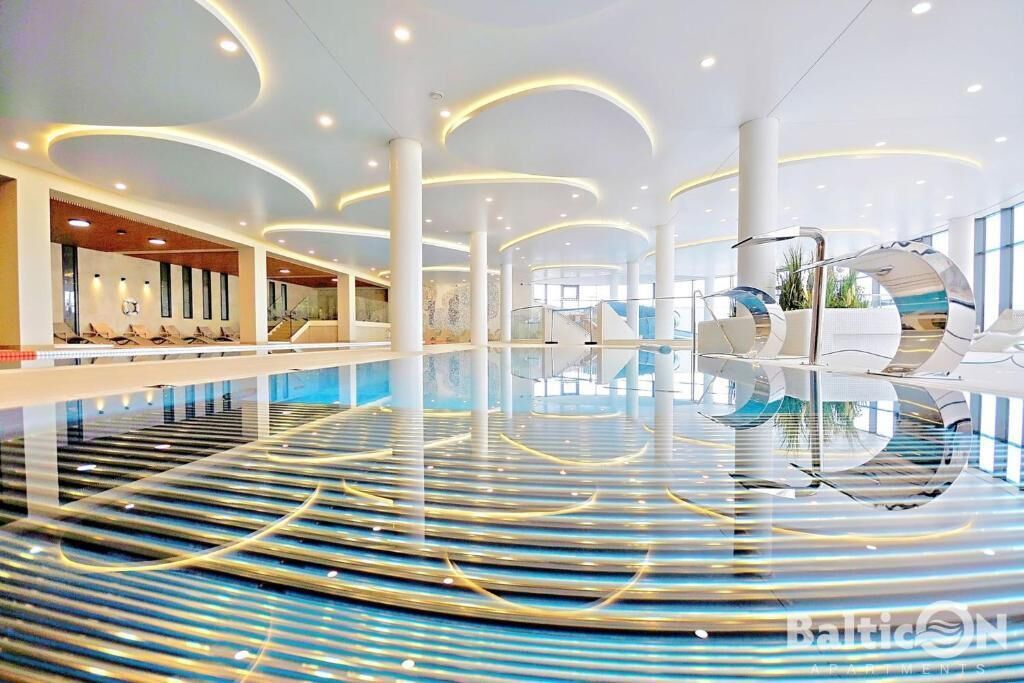 Una amplia piscina interior con diseño moderno, que cuenta con una isla central y zonas de estar a lo largo de los bordes.