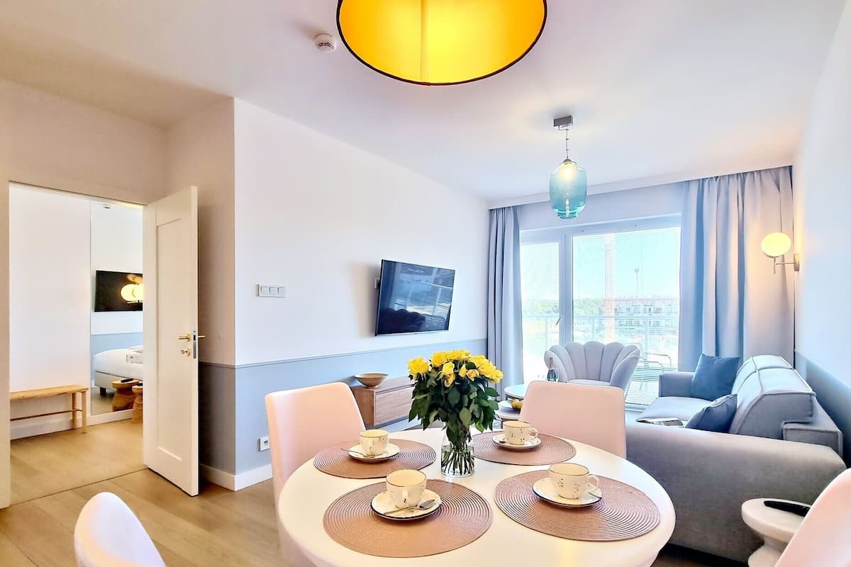 Un soggiorno moderno con zona pranzo, un divano e una TV a parete.