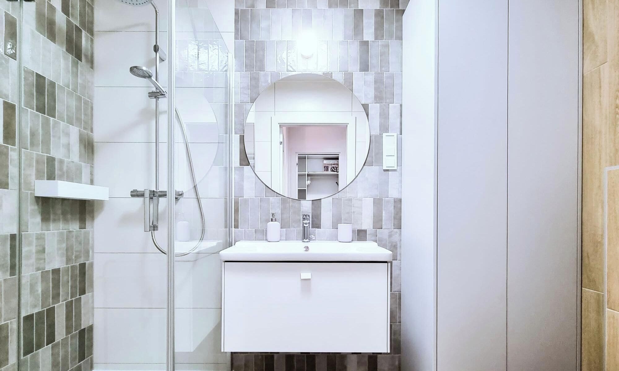 Un baño con cabina de ducha de vidrio, un lavabo blanco y un espejo encima.