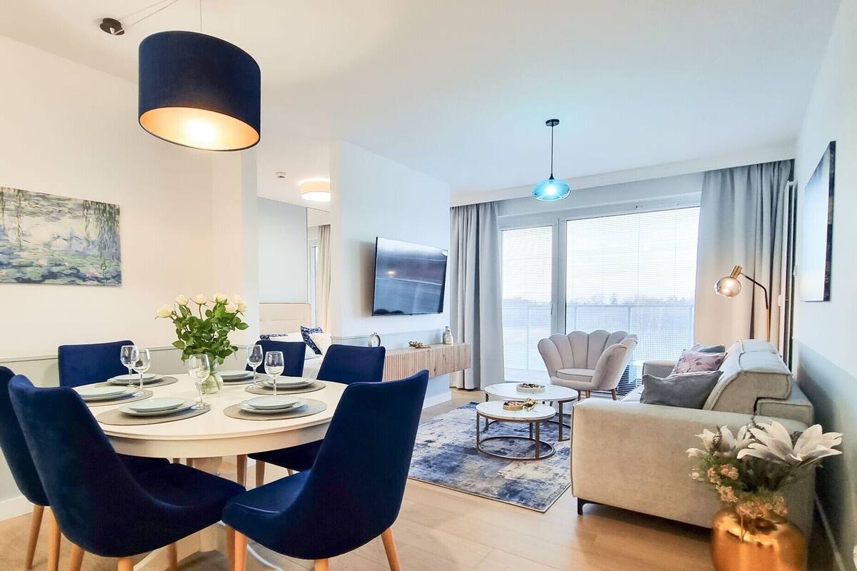 Un soggiorno moderno con zona pranzo, un divano, una TV e un'ampia finestra.