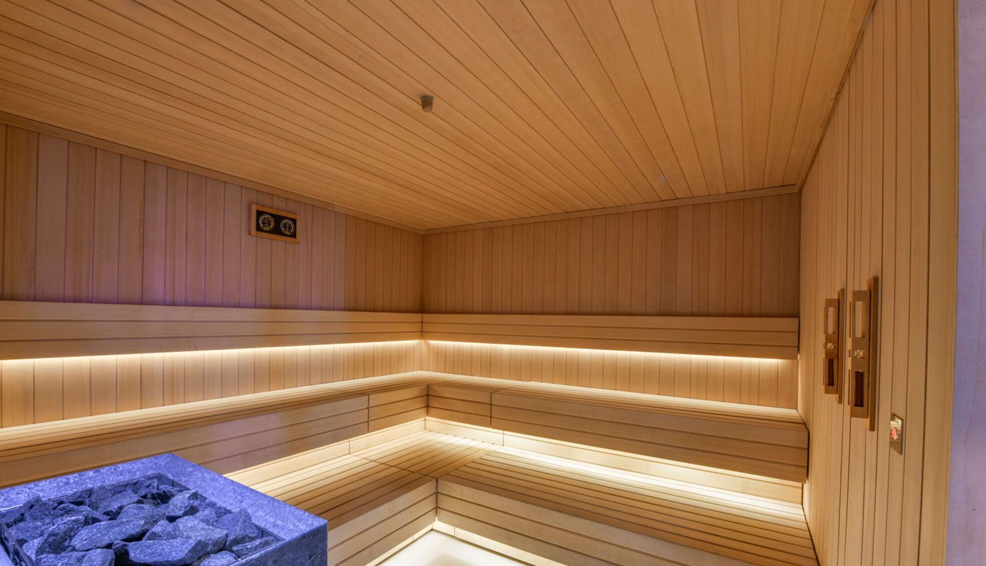 A sauna with wooden walls and benches, a stone basin, and a small plaque on the wall.