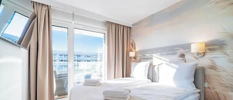 A modern hotel room with a large bed, two bedside lamps, a view of the city through floor-to-ceiling windows, and a painting on the wall.