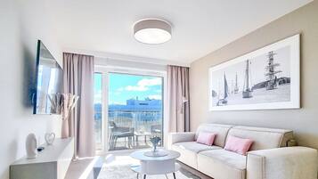 A modern living room with a sofa, a coffee table, and a large window with a view of the city.