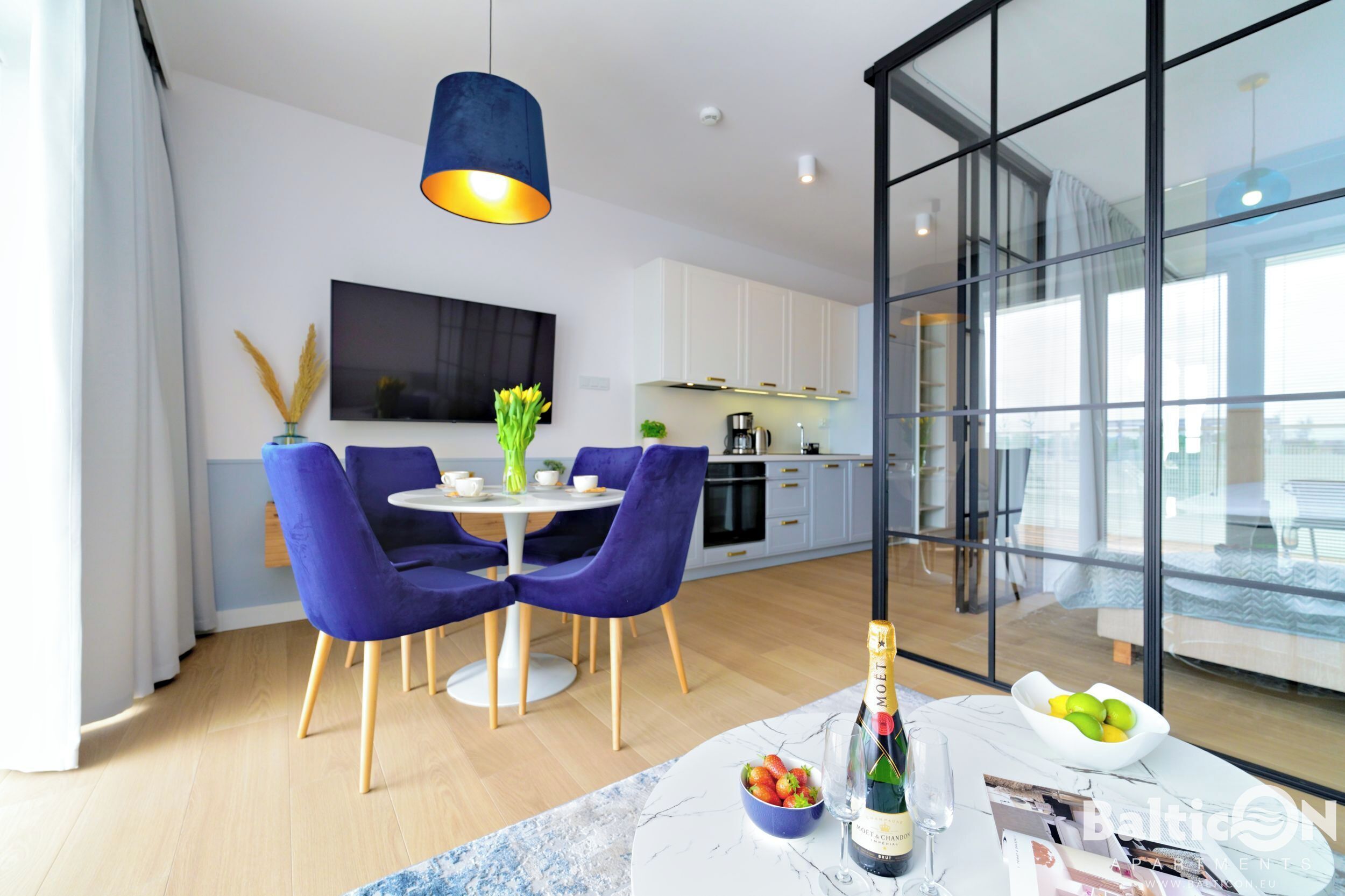A modern dining area with a table, chairs, and a bottle of champagne.