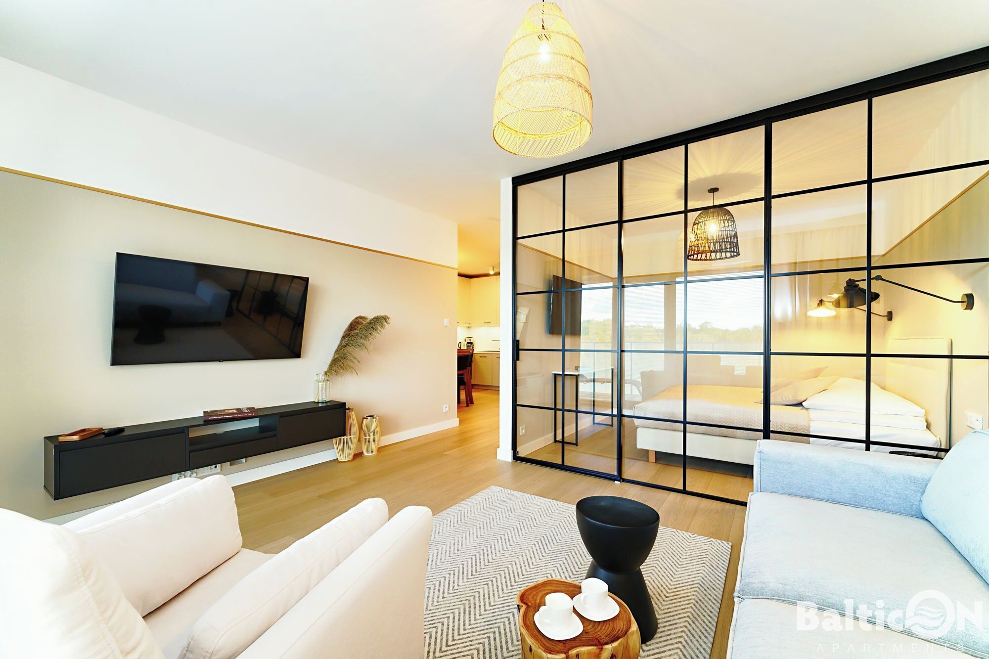 Una sala moderna con un televisor de pantalla plana, un sofá, una mesa de centro y un ventanal con vistas.