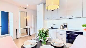 A modern kitchen with white cabinets, a coffee maker, and a dining area with a table set for four.