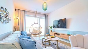 Una sala de estar moderna con un sofá, una silla colgante, un televisor y un mural decorativo con peces.