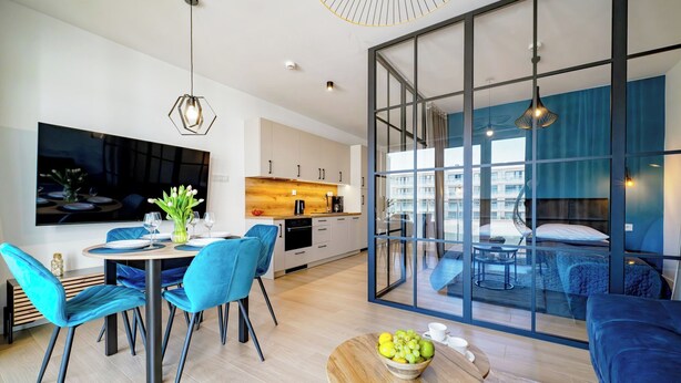 Una sala de estar moderna con comedor, cocina y un gran ventanal que ofrece vistas de la ciudad.