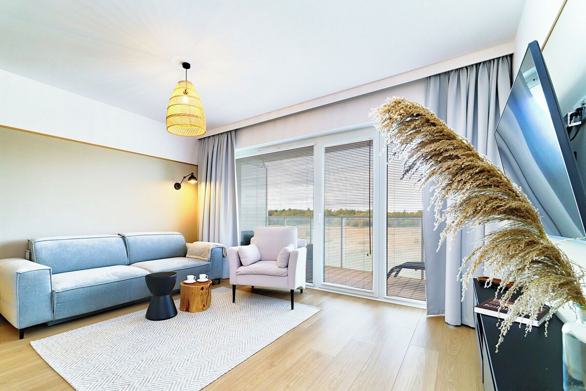 Una sala moderna con sofá, sillón y una planta decorativa.