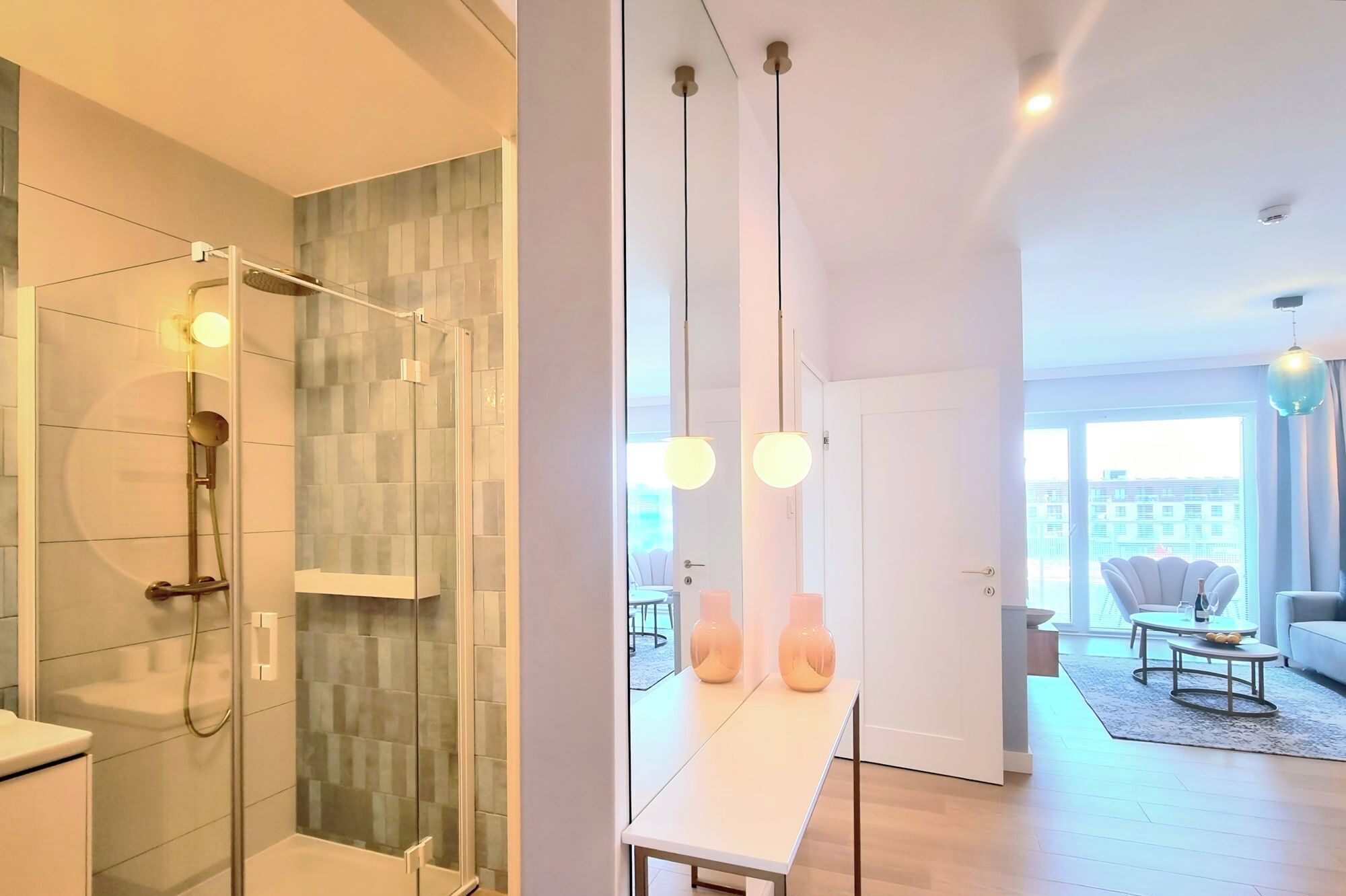 Une salle de bain moderne avec une douche à parois de verre et un meuble-lavabo blanc agrémenté de deux vases.