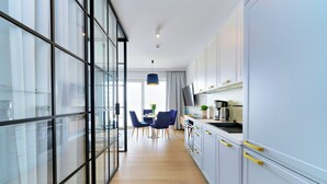 Una cocina moderna con armarios blancos, un comedor con sillas azules y un ventanal grande.