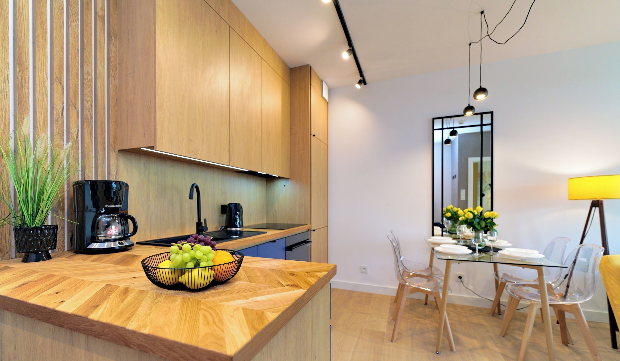 Una cocina moderna con armarios de madera, una cafetera negra y un frutero en la encimera.
