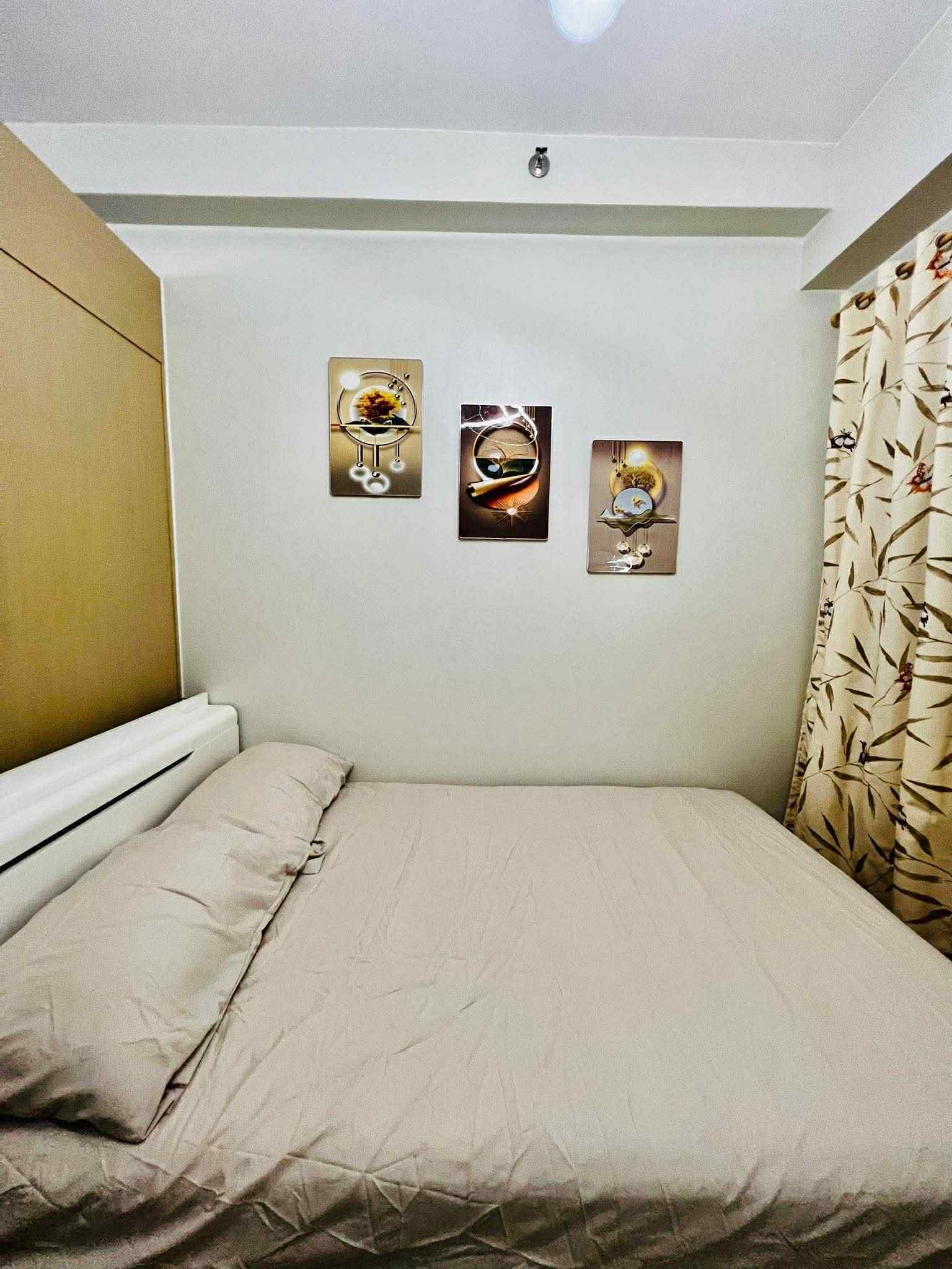 Une chambre à coucher avec un lit, une tête de lit et trois œuvres d’art accrochées au mur.
