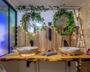 Ein Badezimmer mit zwei großen Steinswaschbecken, Holzvertäfelung und dekorativem Grün.