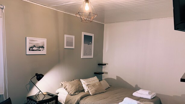 Une chambre à coucher avec un lit, des tables de chevet, une lampe et des œuvres d’art murales.