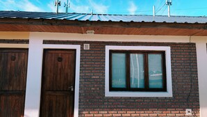 Un bâtiment à deux étages, doté d’une façade en briques, de deux portes en bois et d’une fenêtre à cadre blanc.