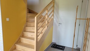 A wooden staircase with a handrail, a white door, and a doormat with "HELLO" written on it. - Spacious new house near the Casino - PLOUESCAT - beach and relaxation (Plouescat)