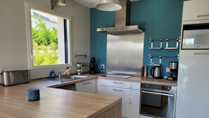 A modern kitchen with a wooden countertop, stainless steel appliances, and a blue accent wall. - Spacious new house near the Casino - PLOUESCAT - beach and relaxation (Plouescat)