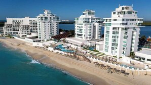 Et strandhotel med flere høje bygninger, en swimmingpool og et strandareal.