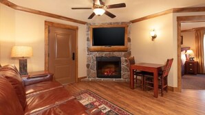 Una sala de estar con chimenea de piedra, sofá de cuero y una mesa de comedor.