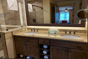 Ein Badezimmer mit zwei Waschbecken, einem großen Spiegel und Holzschränken mit Handtuchhaltern.