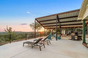 A covered patio with lounge chairs, a barbecue grill, and a view of the landscape. - 20-Mile Hill Country Views, Large Patio & Firepit - Dripping Springs Retreat (Dripping Springs)