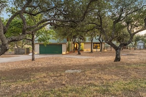 A residential property with a garage, a small house, and mature trees. - Tawnya’s Secret Hideaway | 20-Mile Views (Dripping Springs)
