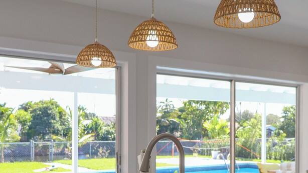 Een moderne keuken met een groot raam, een roestvrijstalen spoelbak en een hanglamp.