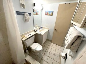 A small, compact bathroom with a toilet, sink, and shower area. - Wonderful Apartment on the Beach (Daytona Beach)