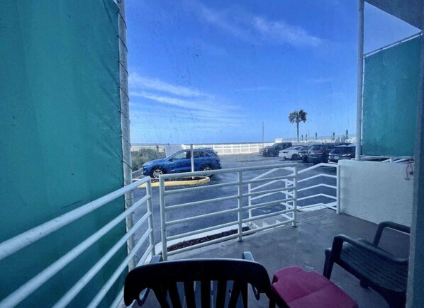 A balcony with a view of a parking lot and a palm tree. - Wonderful Apartment on the Beach (Daytona Beach)