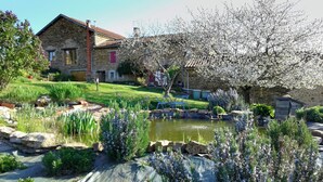 A stone house with a garden, a pond, and a tree with white blossoms. - An eco-renovated house full of charm, a garden and a magnificent view. (Varen)