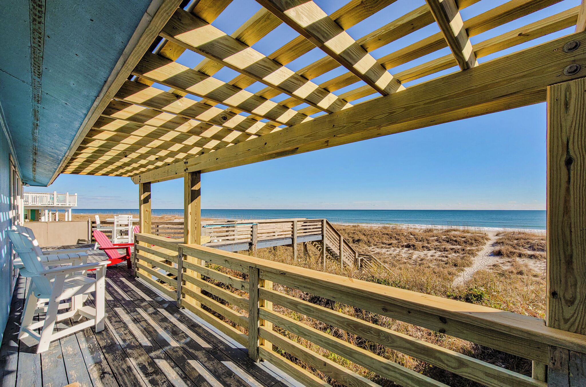 Une terrasse en bois offrant une vue sur la plage et l’océan.