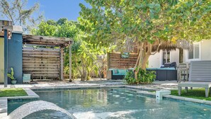 A backyard with a swimming pool, a pergola, and a barbecue area. - NEW Tropical Oasis with Heated Pool & Tiki Hut (Pompano Beach)