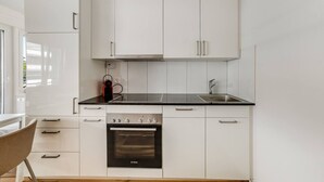 Una cocina moderna con armarios blancos, un horno Bosch, una encimera negra y un lavaplatos de acero inoxidable.