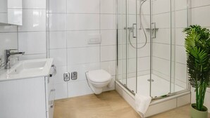 Un baño moderno con ducha envuelta en vidrio, inodoro y lavabo.
