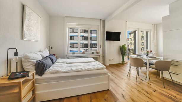 Un dormitorio moderno con cama, mesita de noche y un escritorio con sillas.