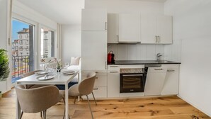 A compact kitchen with white cabinets, a black countertop, and a built-in oven. - Stylish studio apartment near the Olma trade fair (St. Gallen)