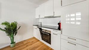 Una cocina moderna con armarios blancos, encimera negra y horno empotrado.