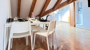 A dining area with a wooden ceiling, white chairs, and a table set for four. - Cozy 2.5 room apartment in Winterthur (Winterthur)