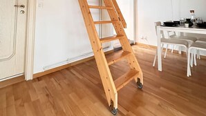 A wooden ladder in a room with wooden floors, white walls, and a white door. - Cozy 2.5 room apartment in Winterthur (Winterthur)